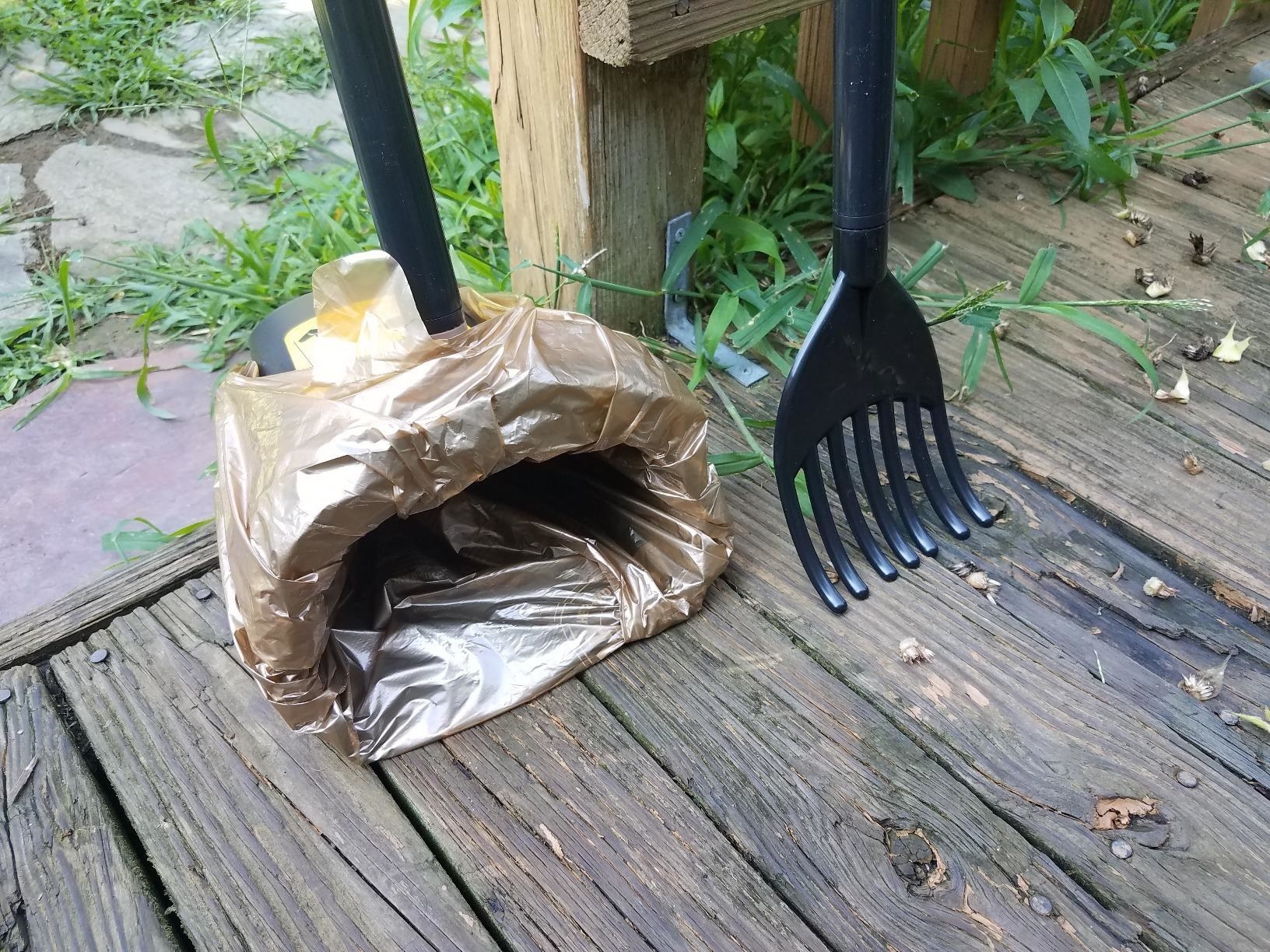 A reviewer&#x27;s black rake and bin with a yellow box of bags