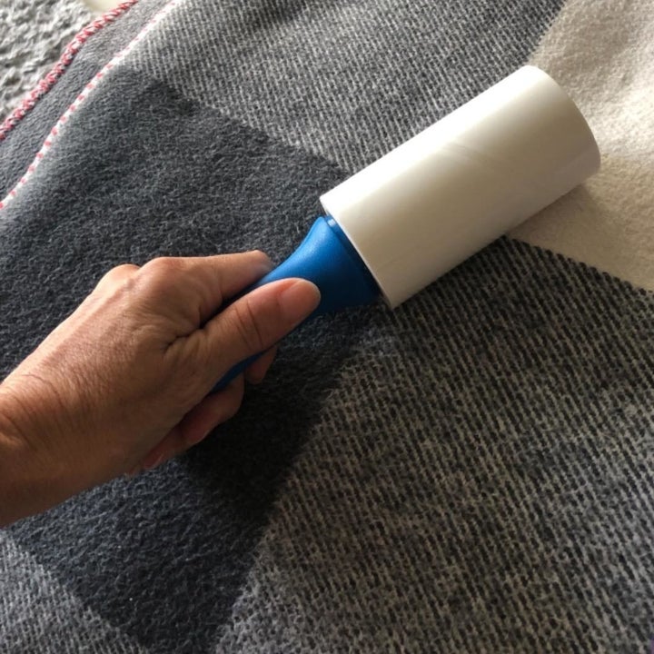 a reviewer photo of a hand using the roller on a blanket