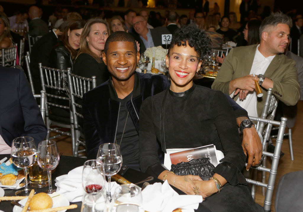 Usher and wife Grace sitting at an event dinner