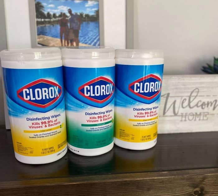 A reviewer&#x27;s photo of a yellow, green, and another yellow jar of wipes