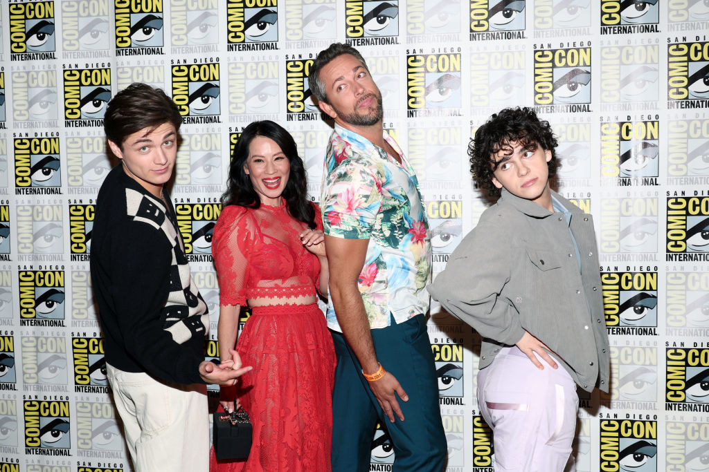 The Shazam family playfully posing on the red carpet by looking over their shoulders