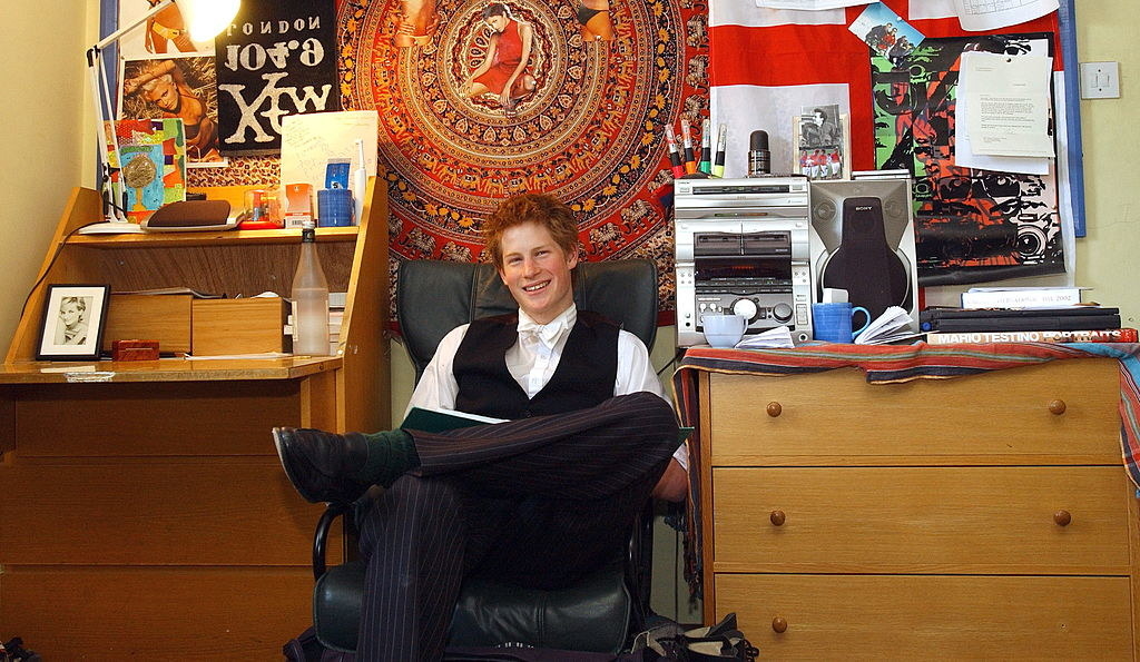 prince harry sitting in a desk chair in a dorm room