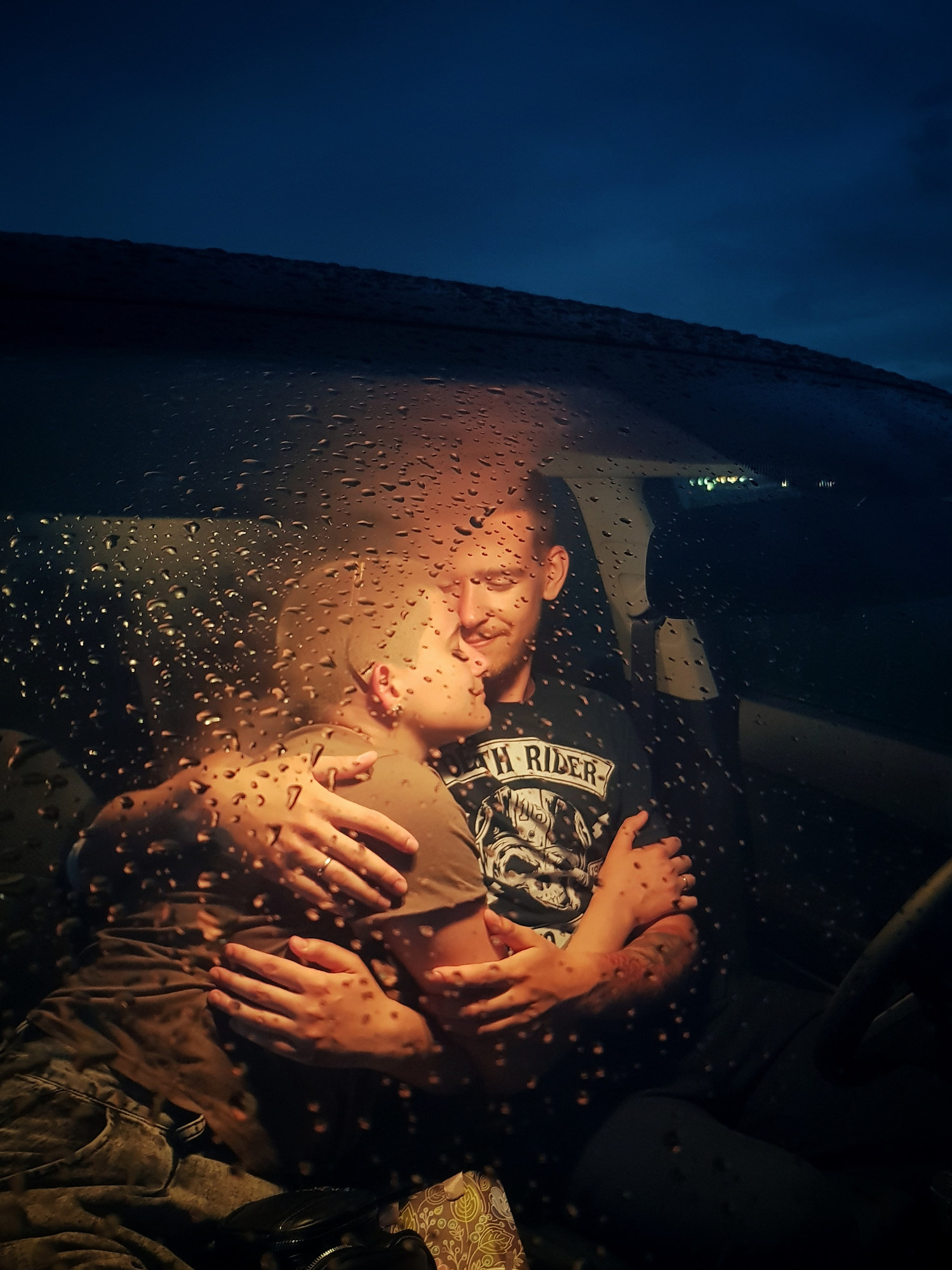 two people cozy up in a car while it rains outside