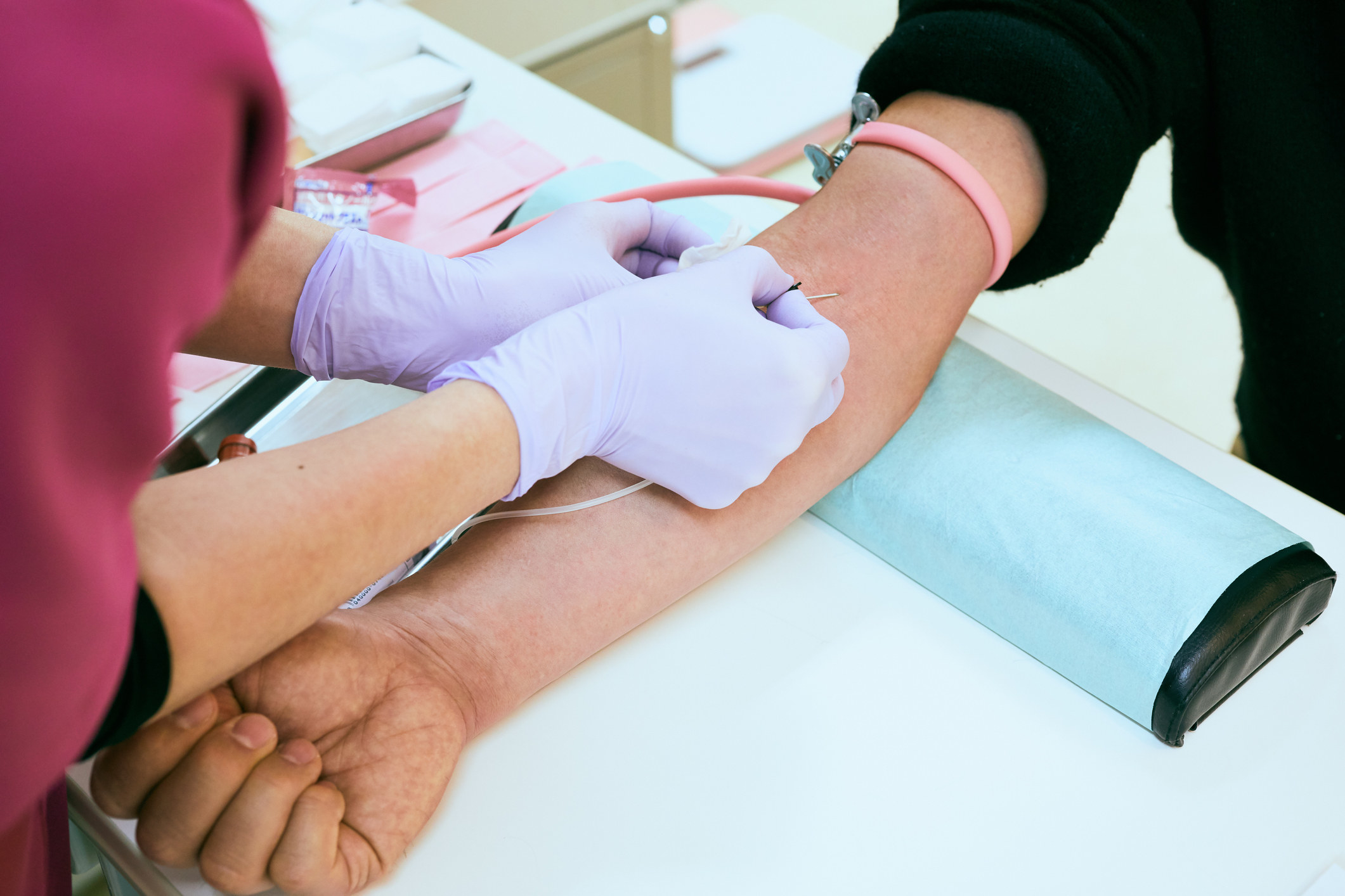 close up of someone sticking a needle in someone&#x27;s arm