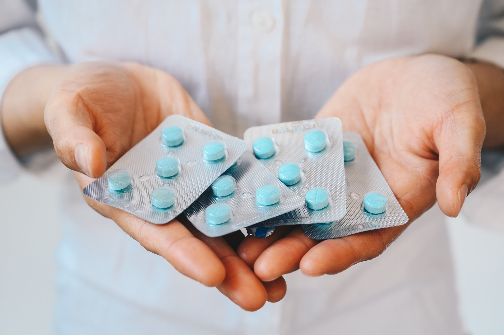 hands holding packets of pills