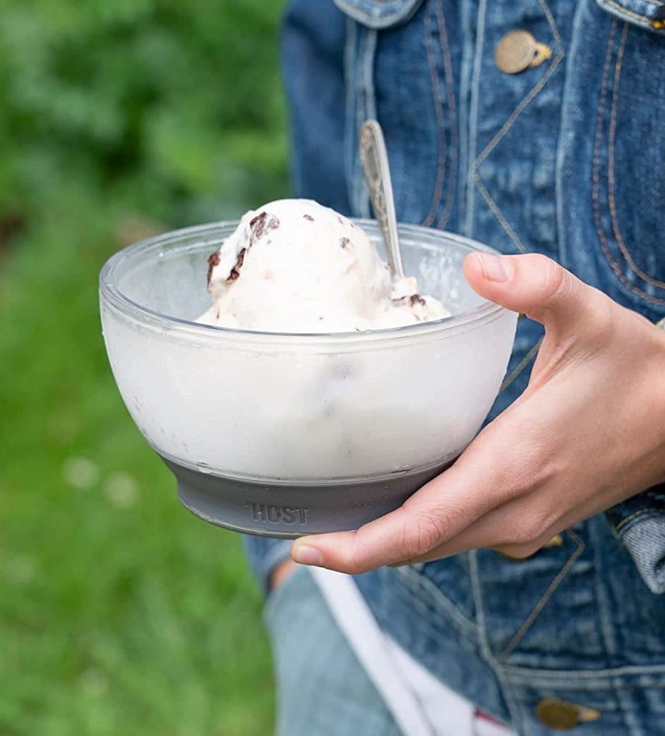 A person holding the bowl full of ice cream