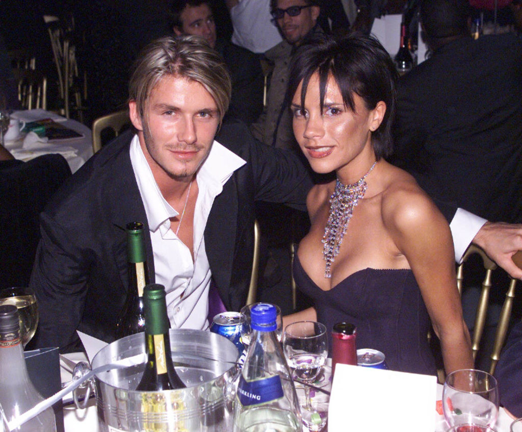 David and Victoria, with spiked bangs, sitting together at a table with various beverages