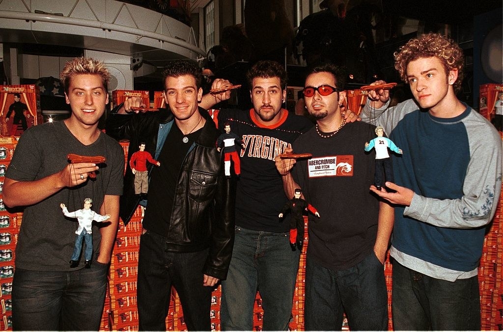 NSYNC standing together and holding the dolls