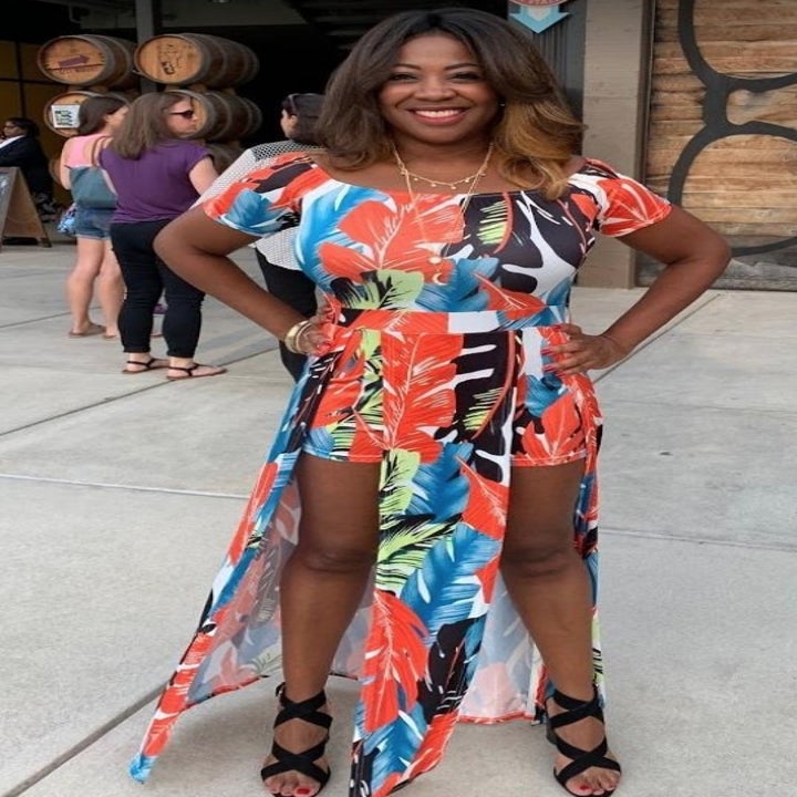 A reviewer wearing the same romper dress in orange floral