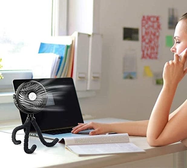 the fan on a desk pointed at a person while they work