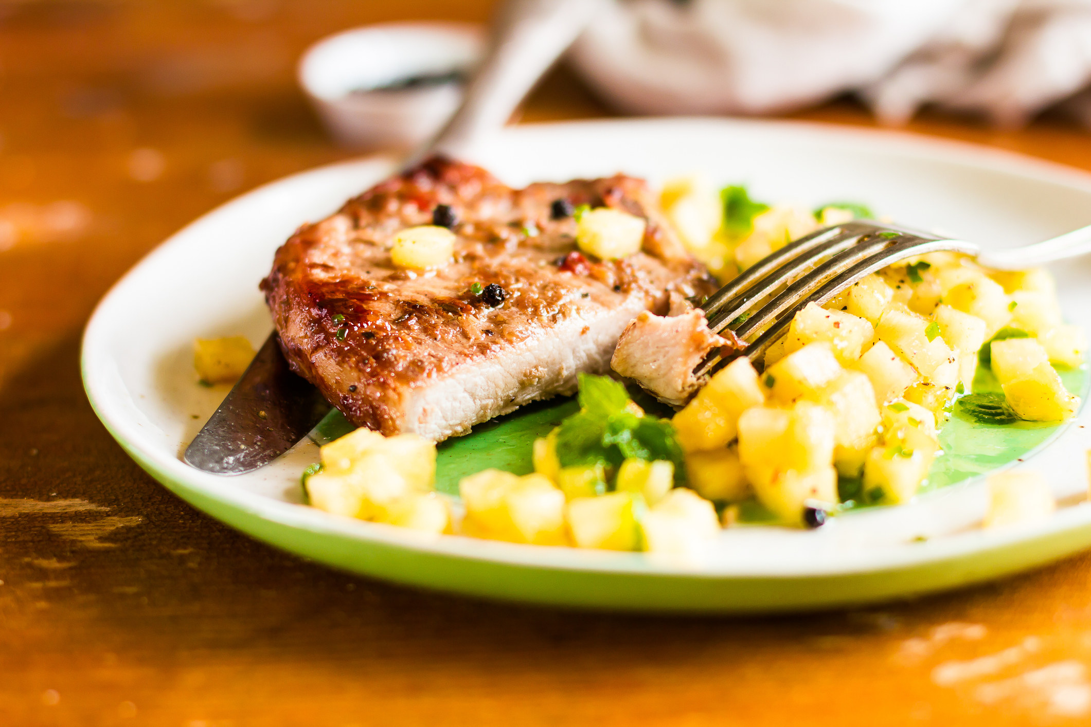 Slicing a pork chop with pineapple salsa and mint.