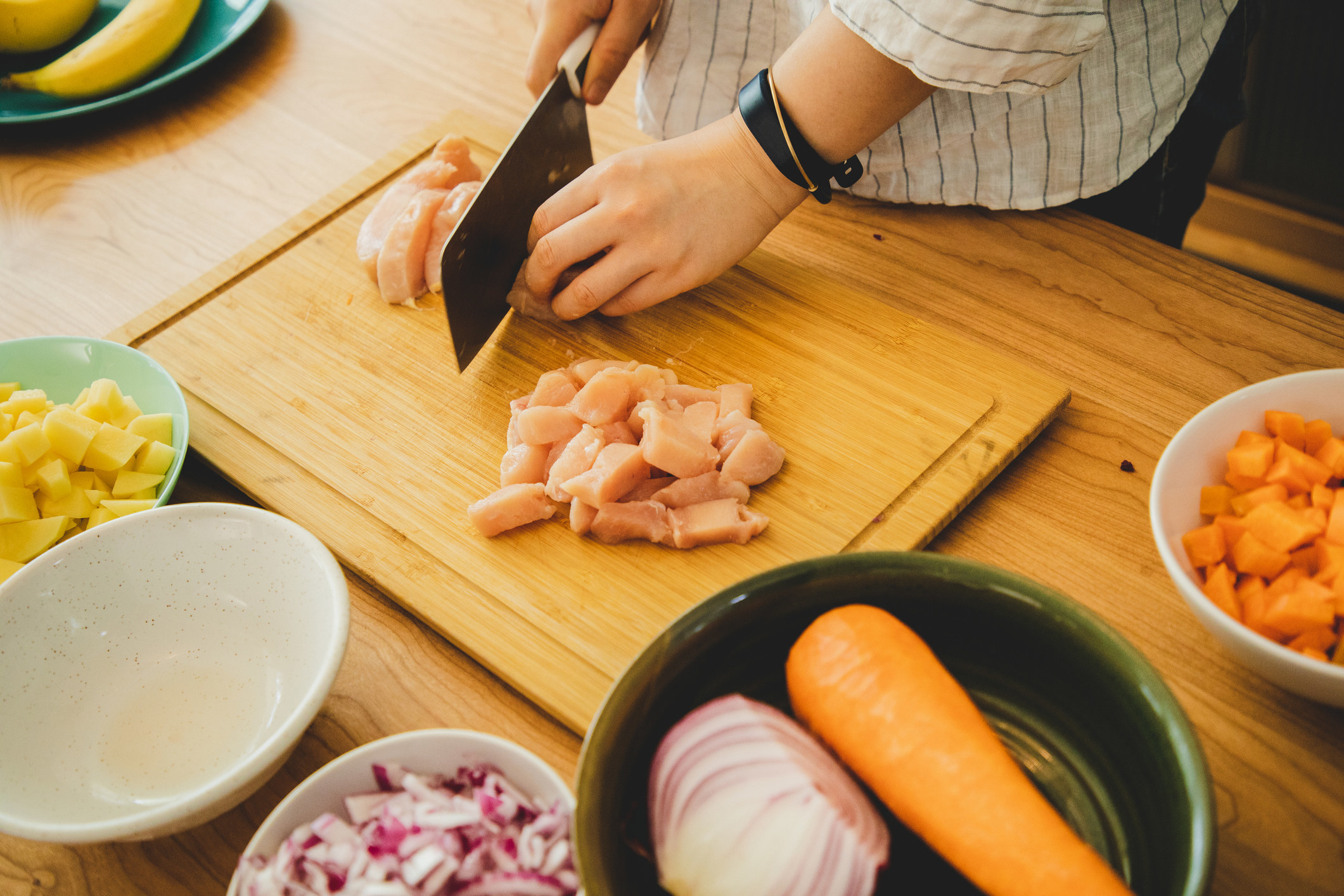 A woman slicing raw chicken.