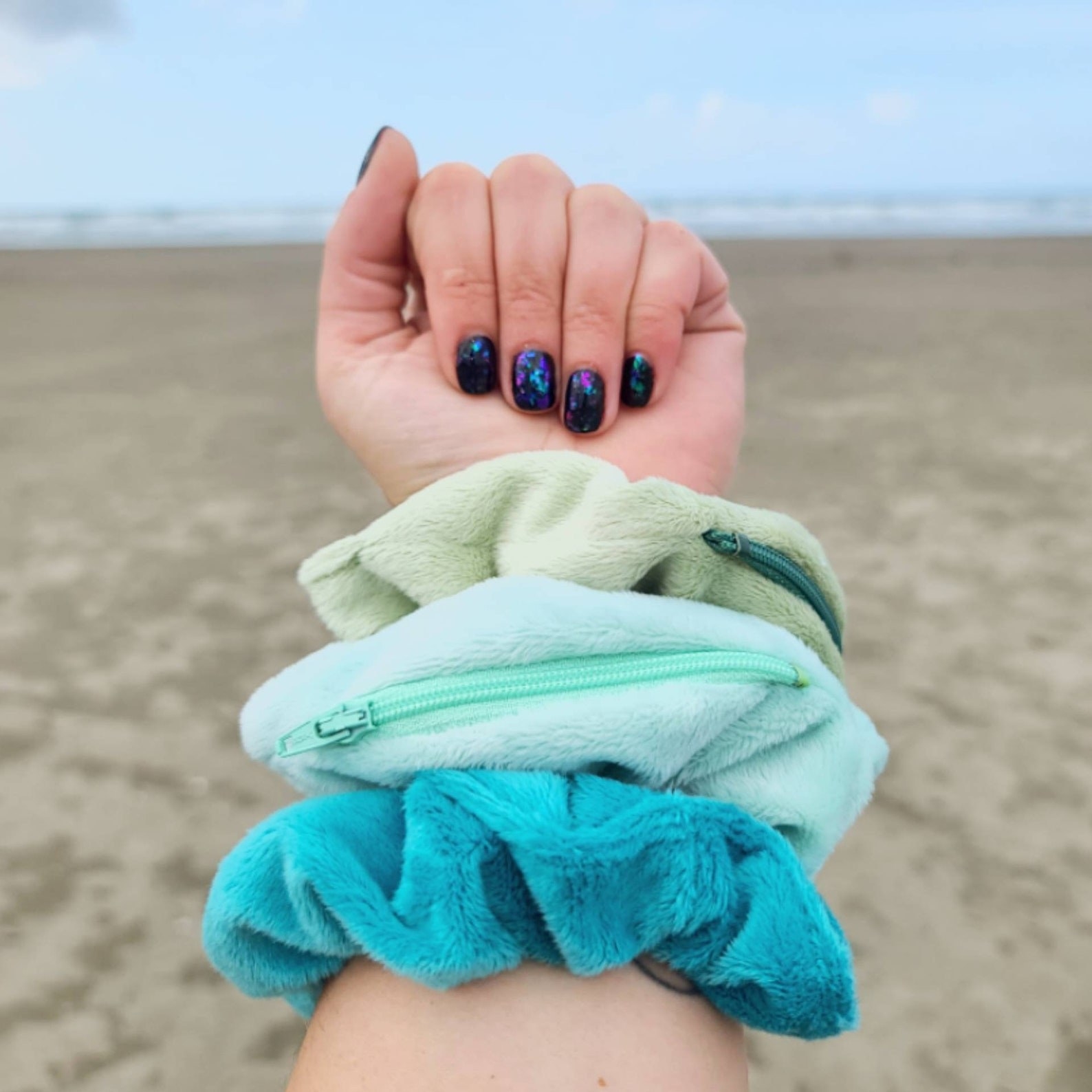 Three stash scrunchies on models arm. Trom top to bottom: light green, light blue, blue scrunchies