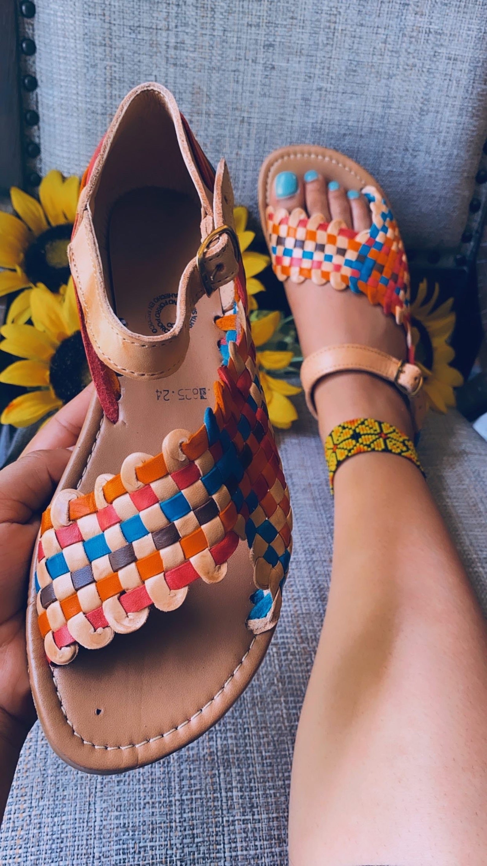 Model wearing rainbow checkerboard sandals with tan leather sole and straps