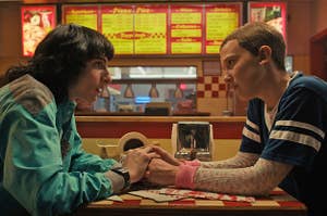 Mike and El from Stranger Things holding hands across the table