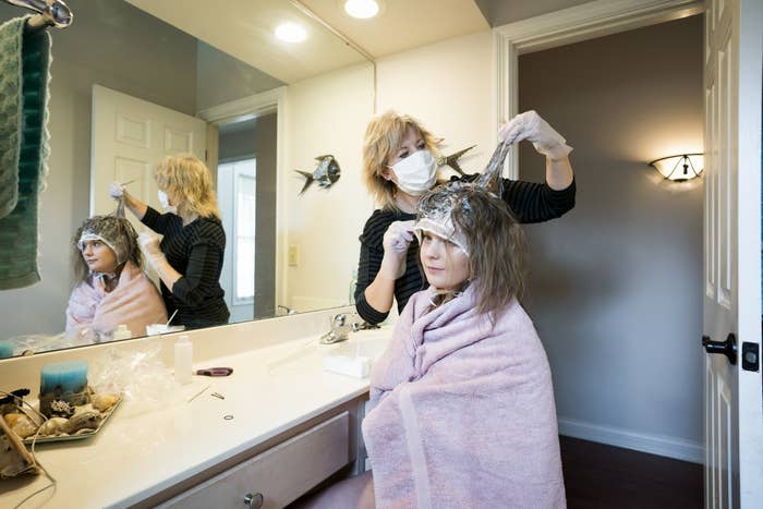 A mom cutting her child&#x27;s hair in their bathroom