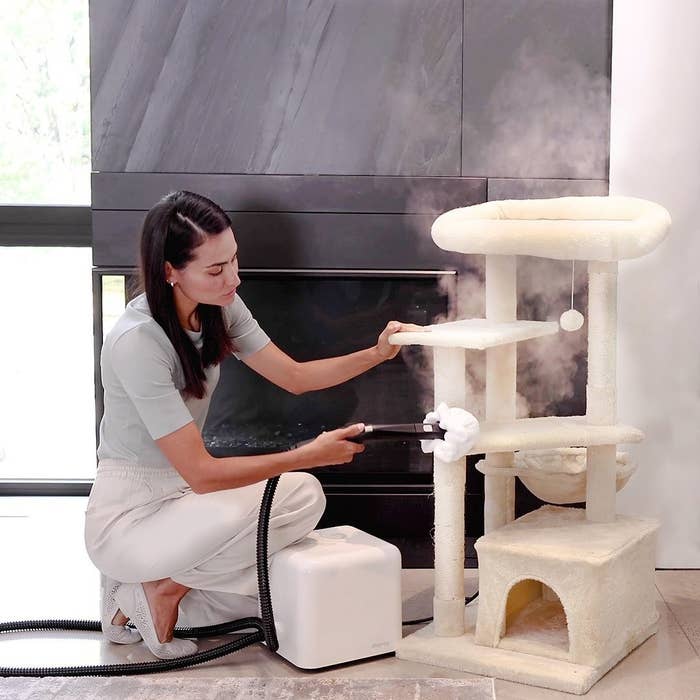 person using the steamer to clean their cat tower