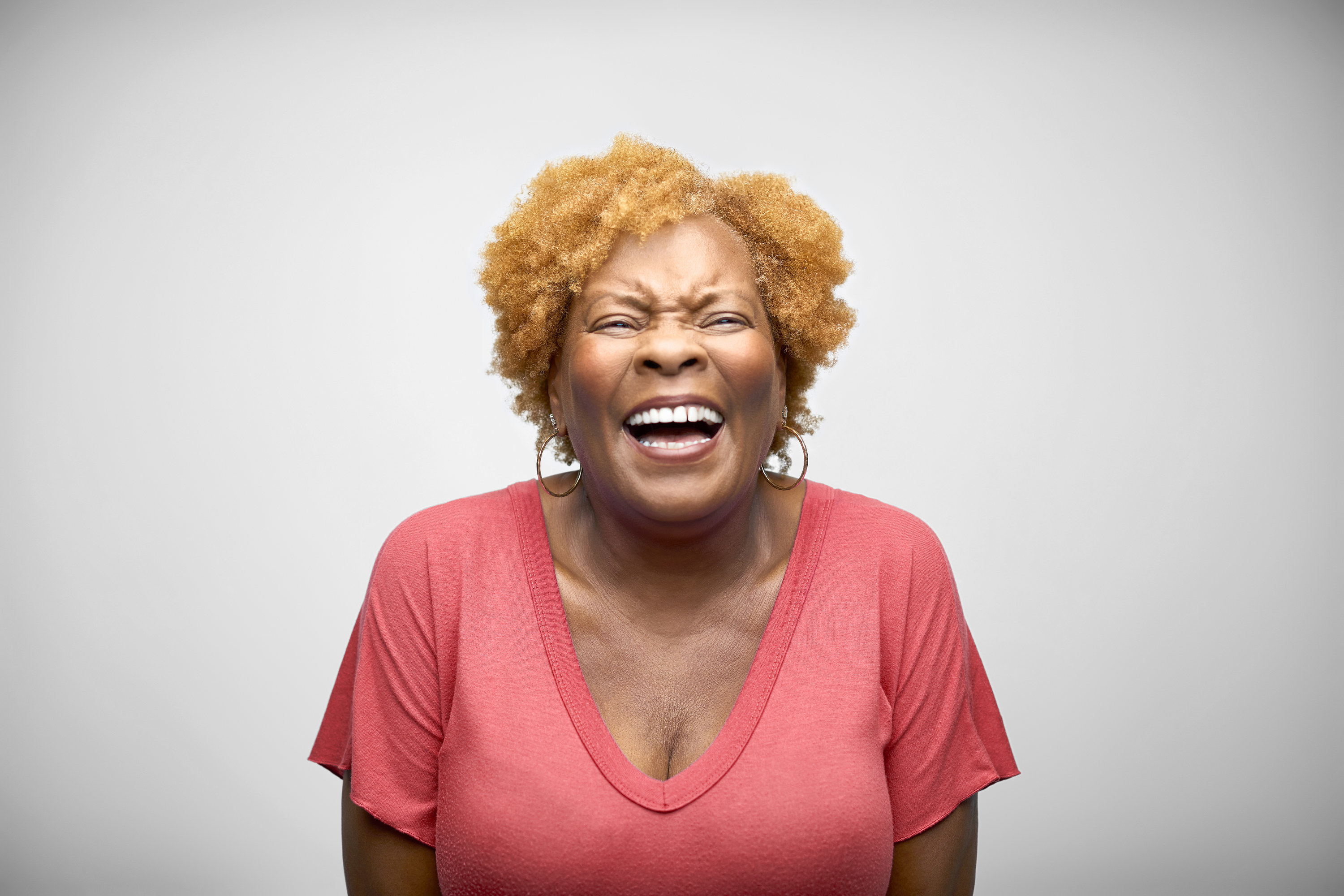Mature African American woman laughing against white background