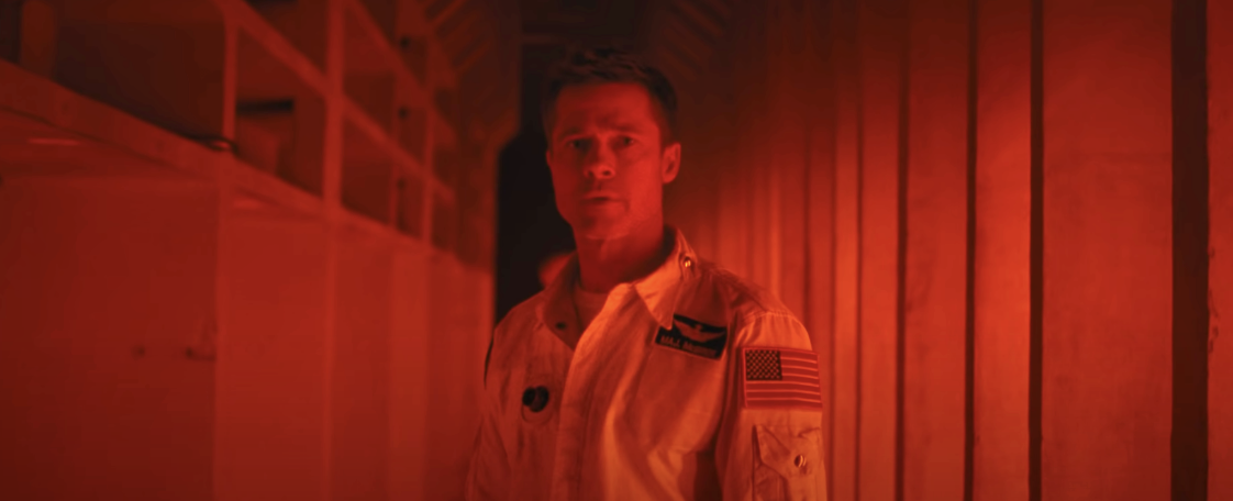 Brad Pitt in a space suit under red lights