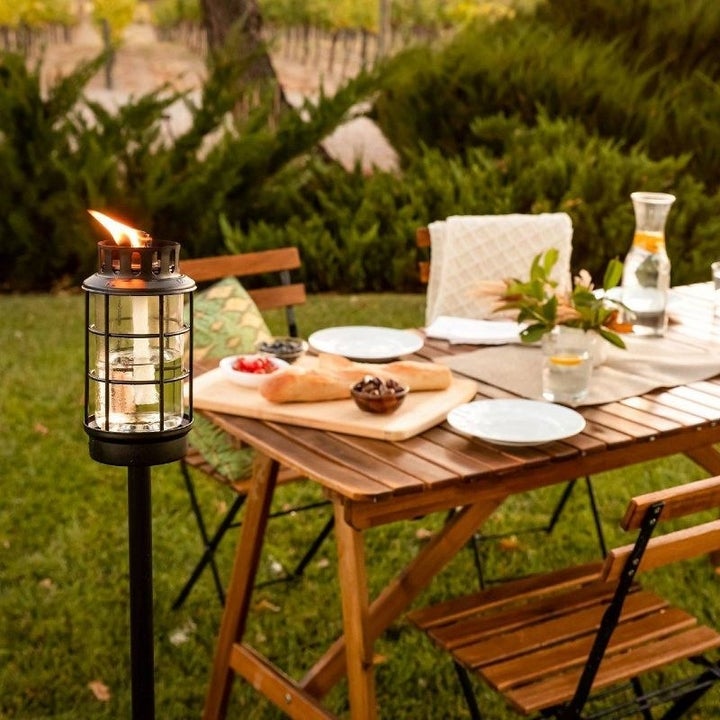 the torch next to an outdoor dining set