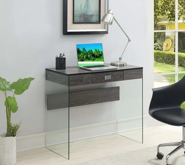 a weathered gray glass desk with a laptop and lamp on top