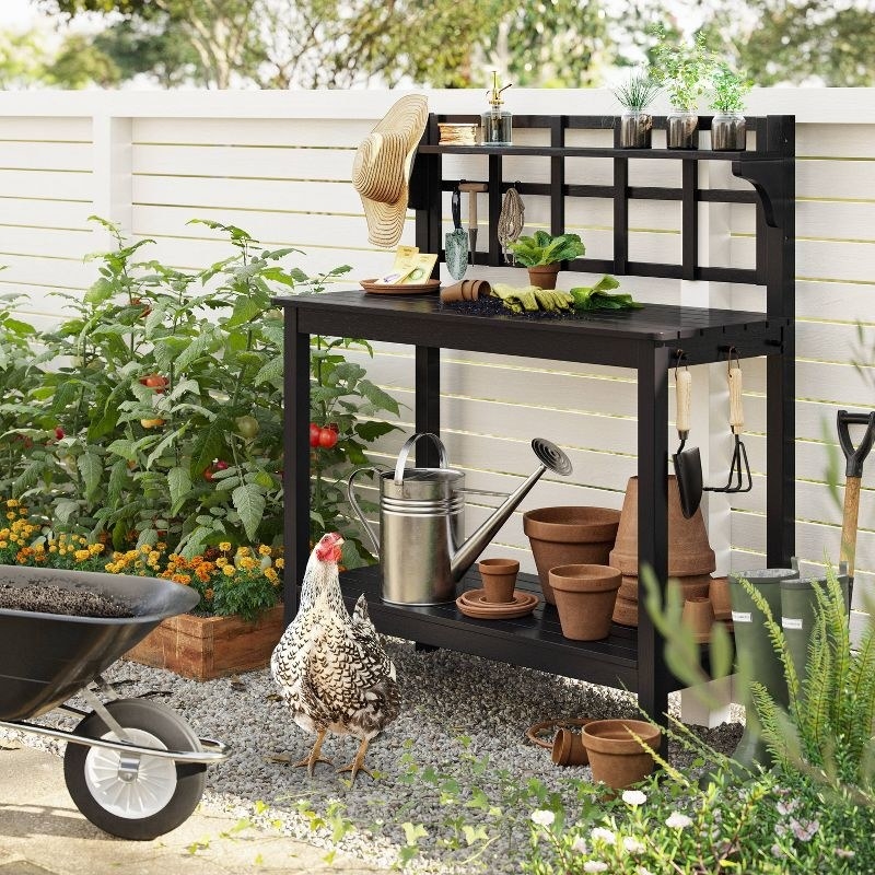 a wooden patio bench outside with gardening tools and chicken