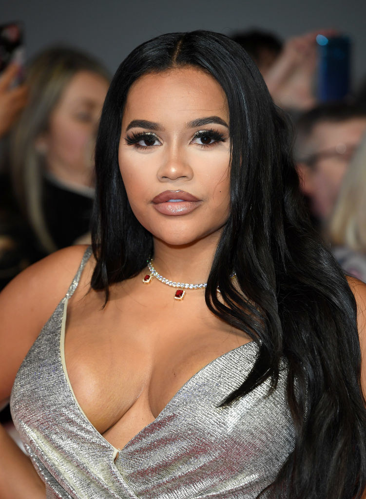 Lateysha Grace posing on red carpet in a silver plunged dress.