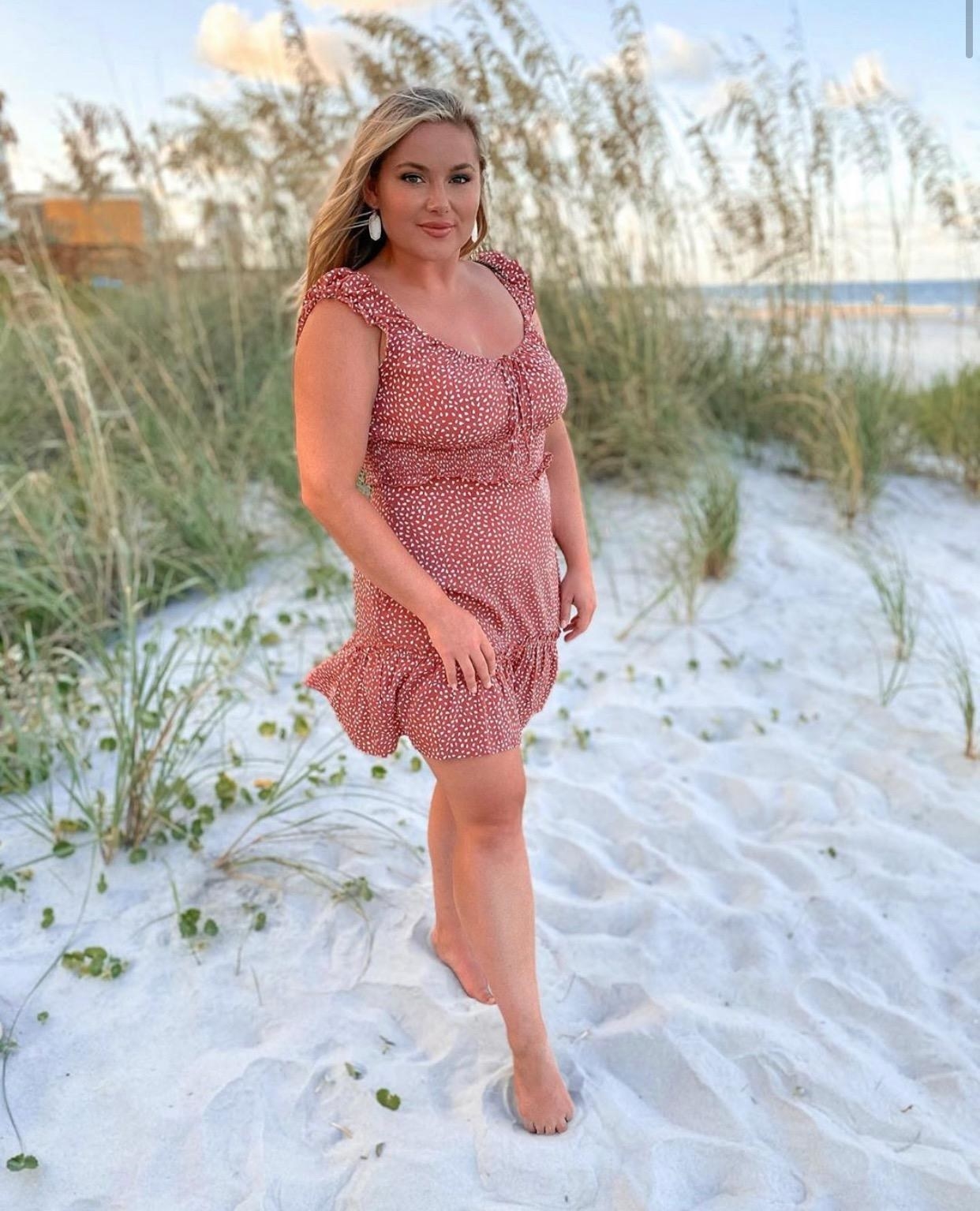 Reviewer wearing red and white dress on the beach