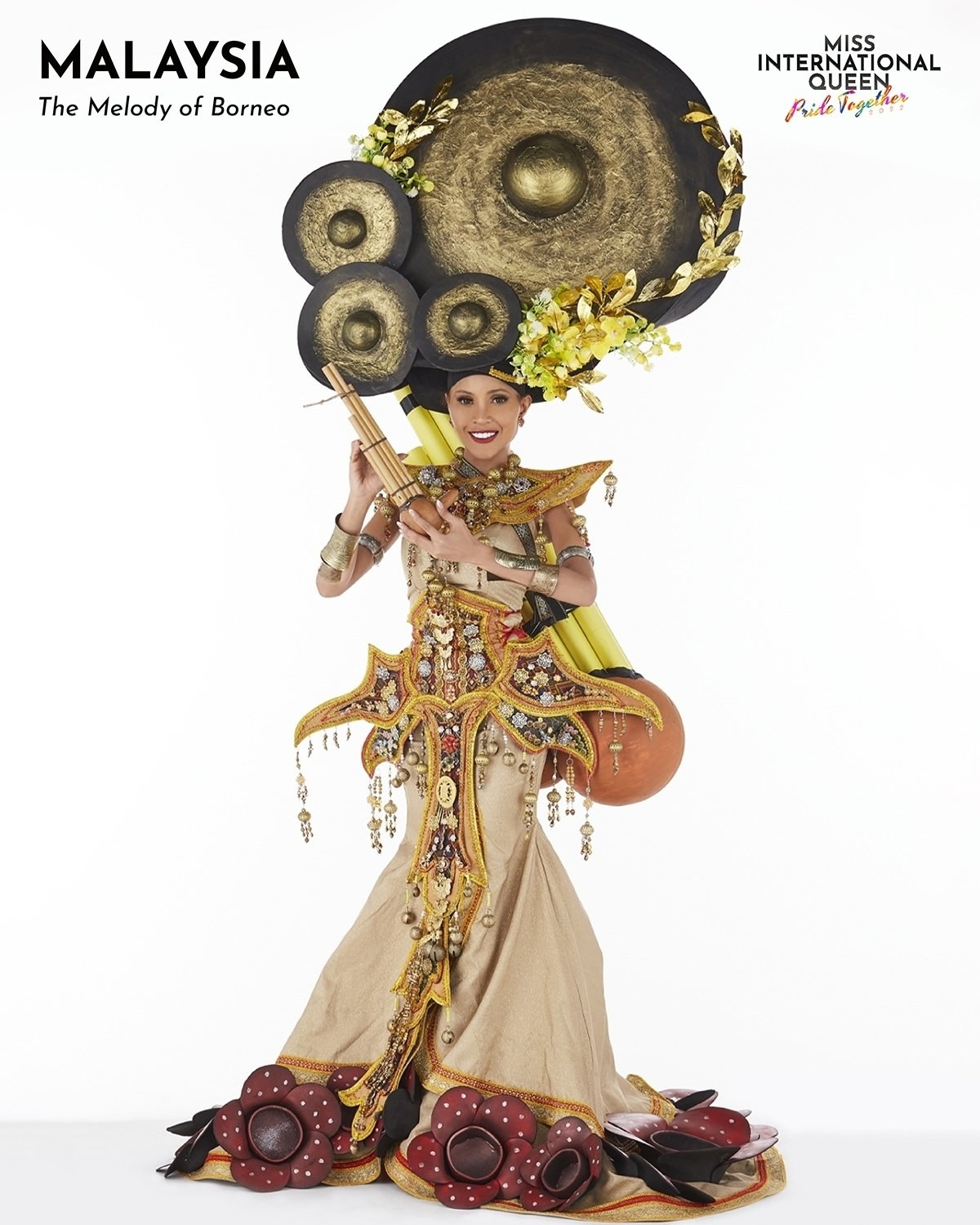 Miss Malaysia in a gold and beige dress with flowers and a really big gong headpiece