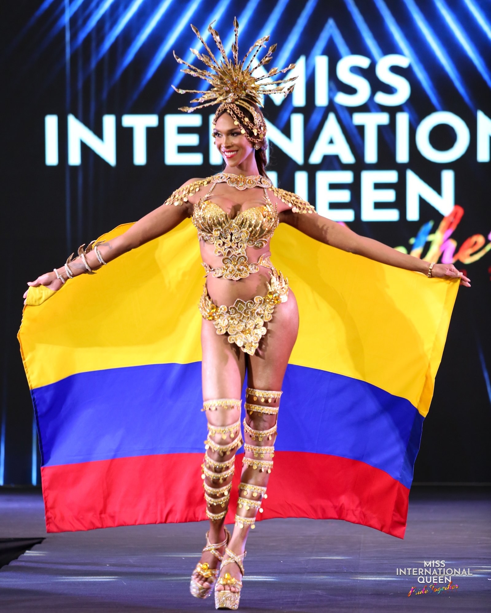 Miss Colombia walks the runway in the gold outfit while holding her nation&#x27;s flag
