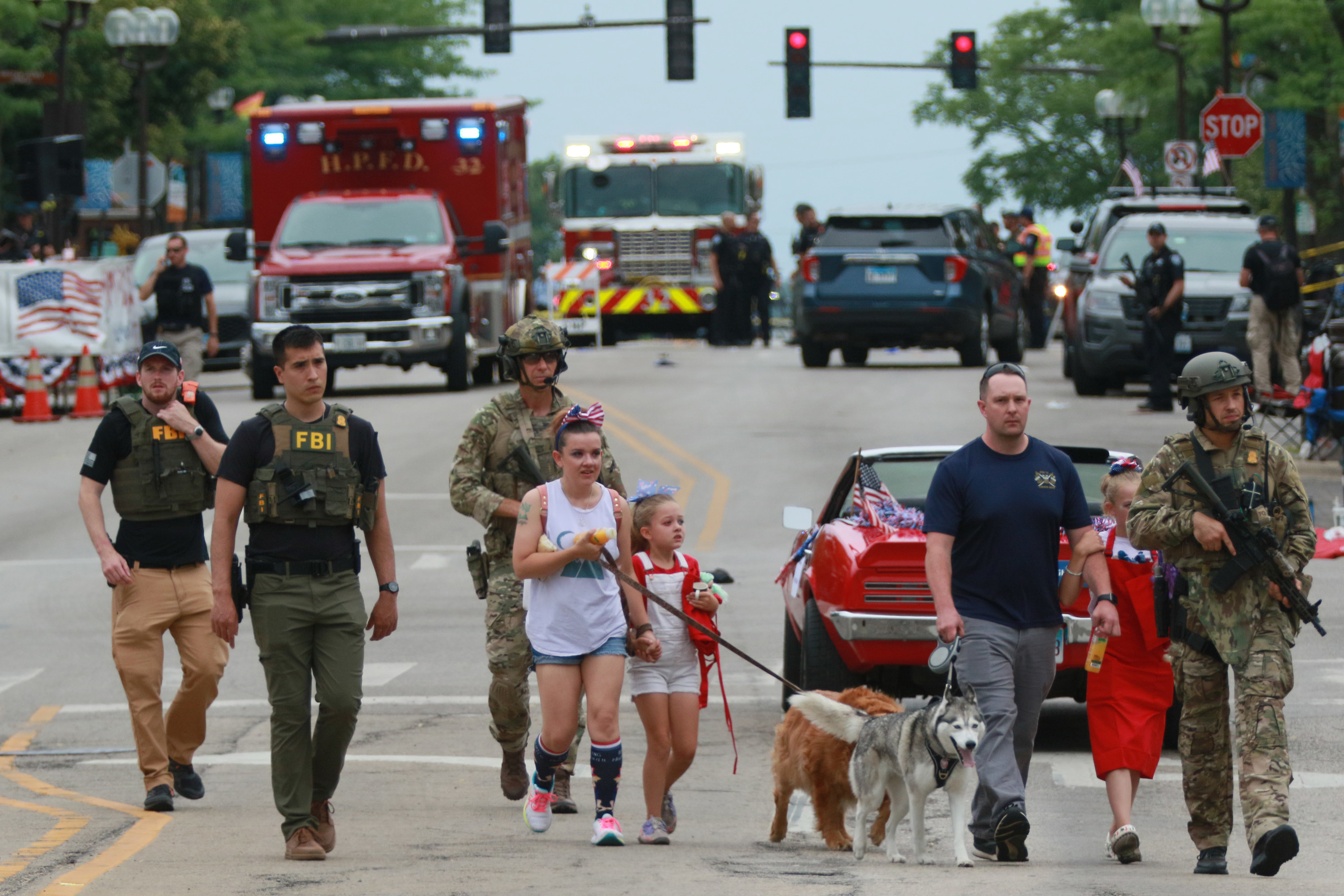 Law enforcement escorts a family away from the scene of a shooting at a Fourth of July parade on July 4, 2022 in Highland Park, Illinois.