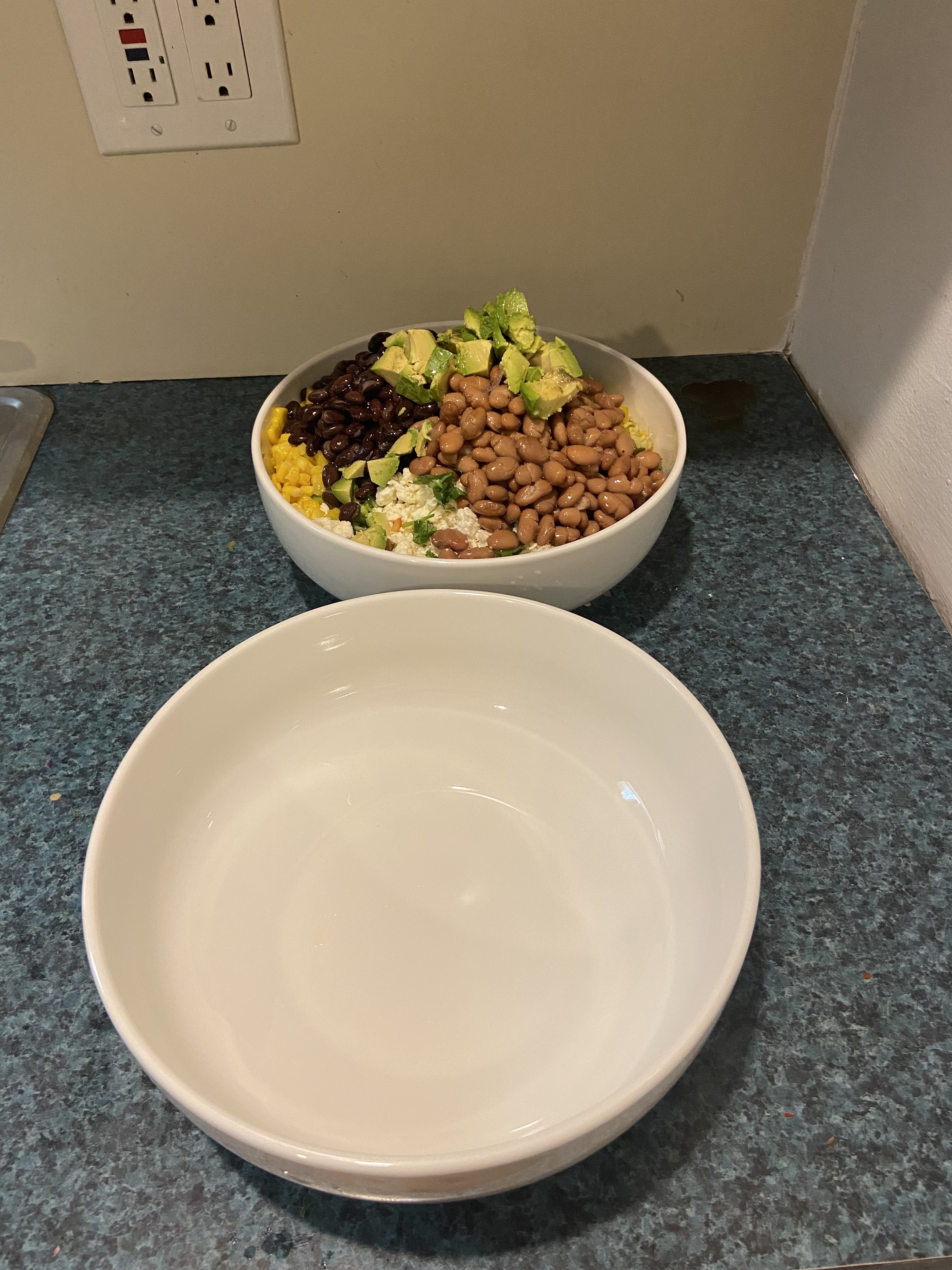 A bigger empty bowl next to a smaller one with food in it