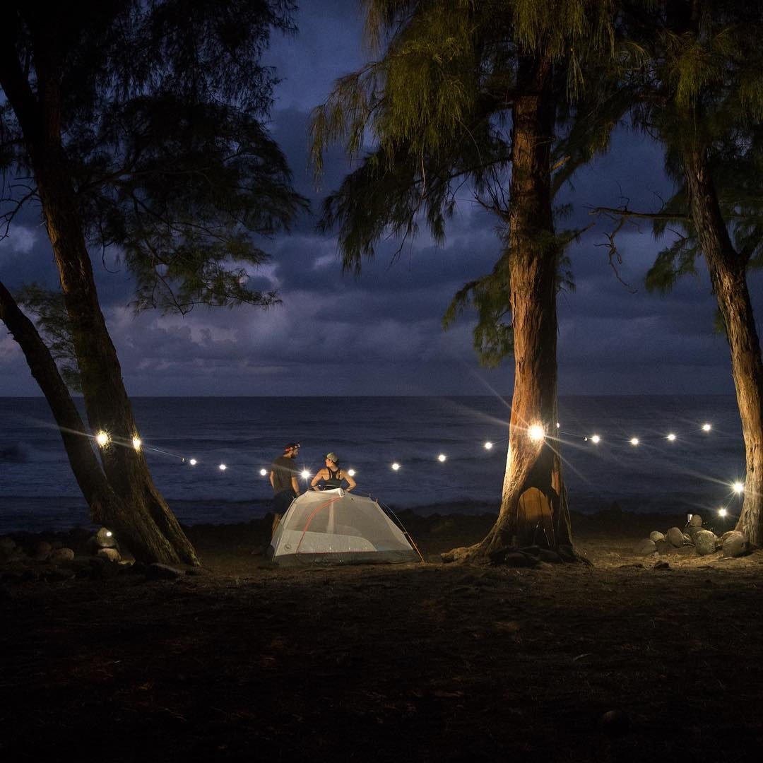 A beach campsite surrounded by string lights