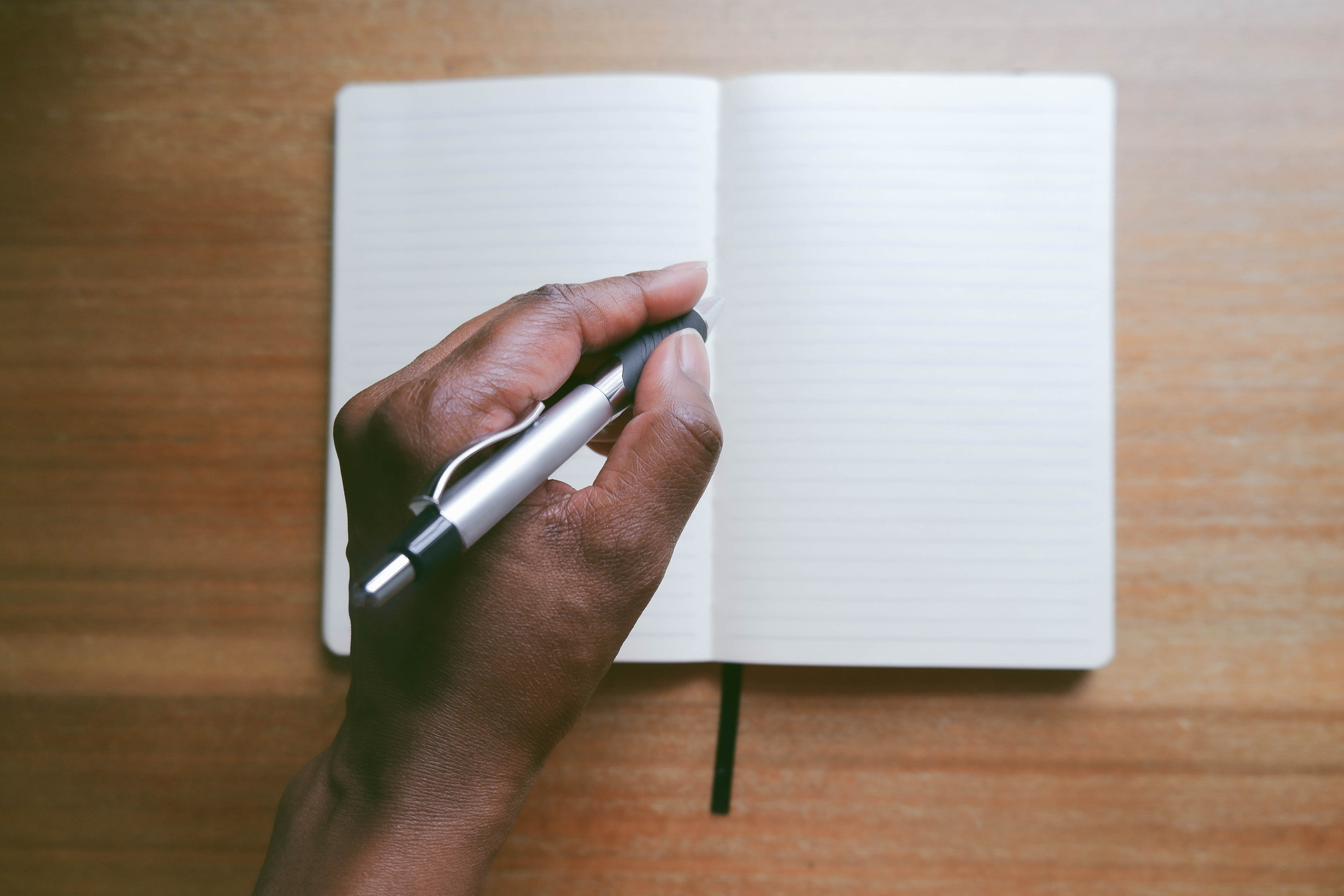 A person holding a pen over a journal