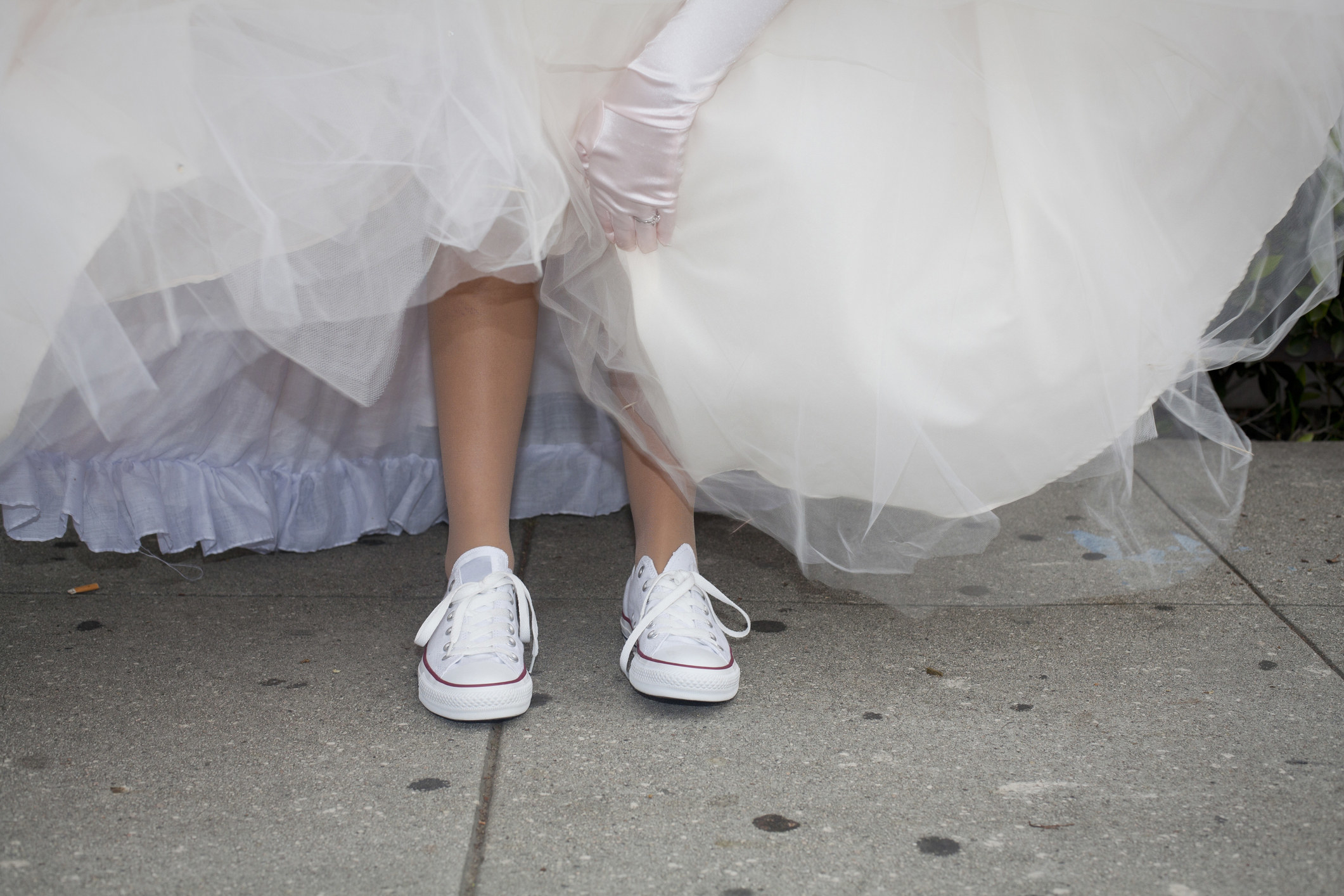 A bride wearing Converse under her wedding gown