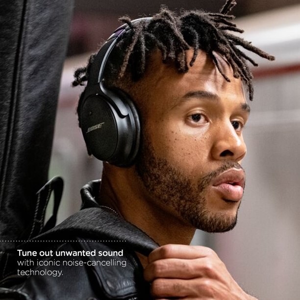 Model wearing the black over-ear headphones and pulling coat up. text on image reads &quot;tune out unwanted sound with iconic noise-cancelling technology&quot;