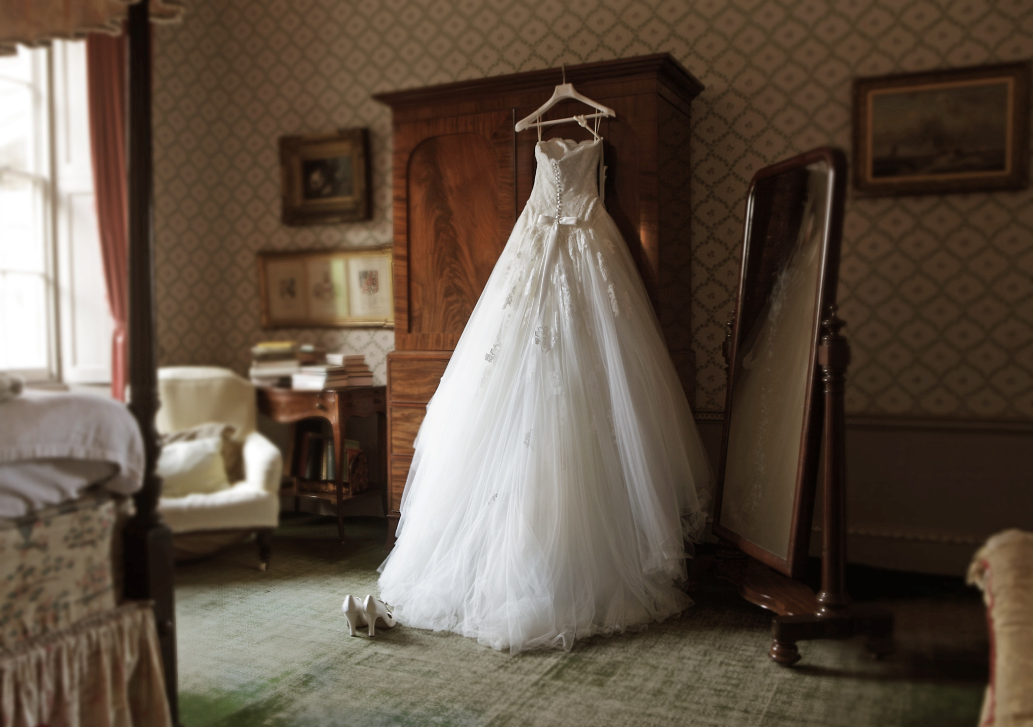 A wedding dress hanging on an armoire.