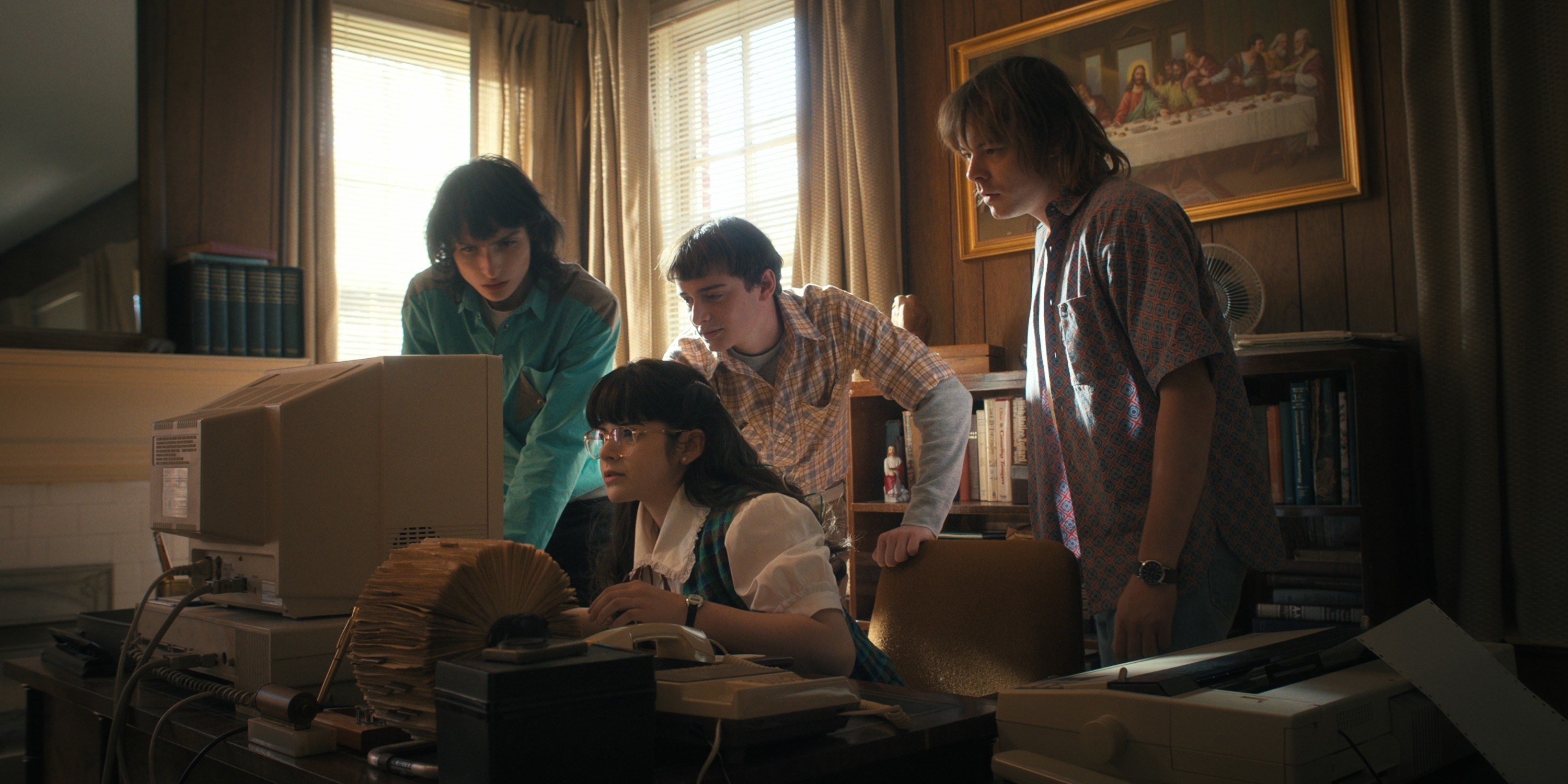 four of the characters huddled around a computer