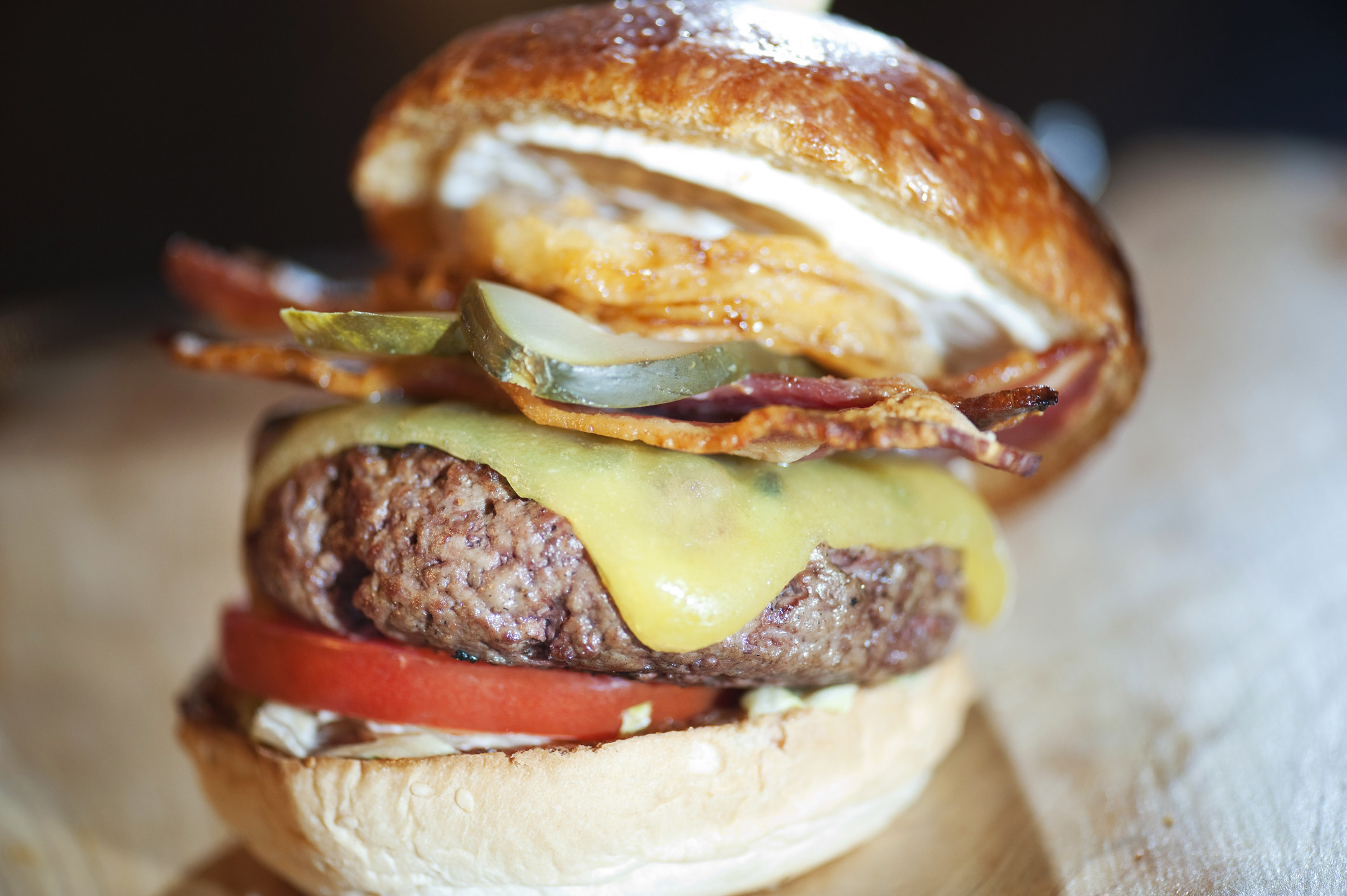 A thick hamburger with onion ring, bacon, tomatoes and pickle
