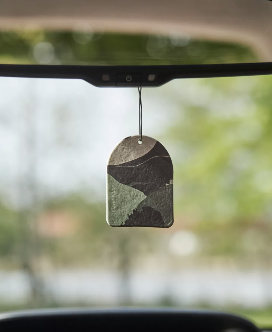 a close up of the scent tag hung from the rearview mirror of a car