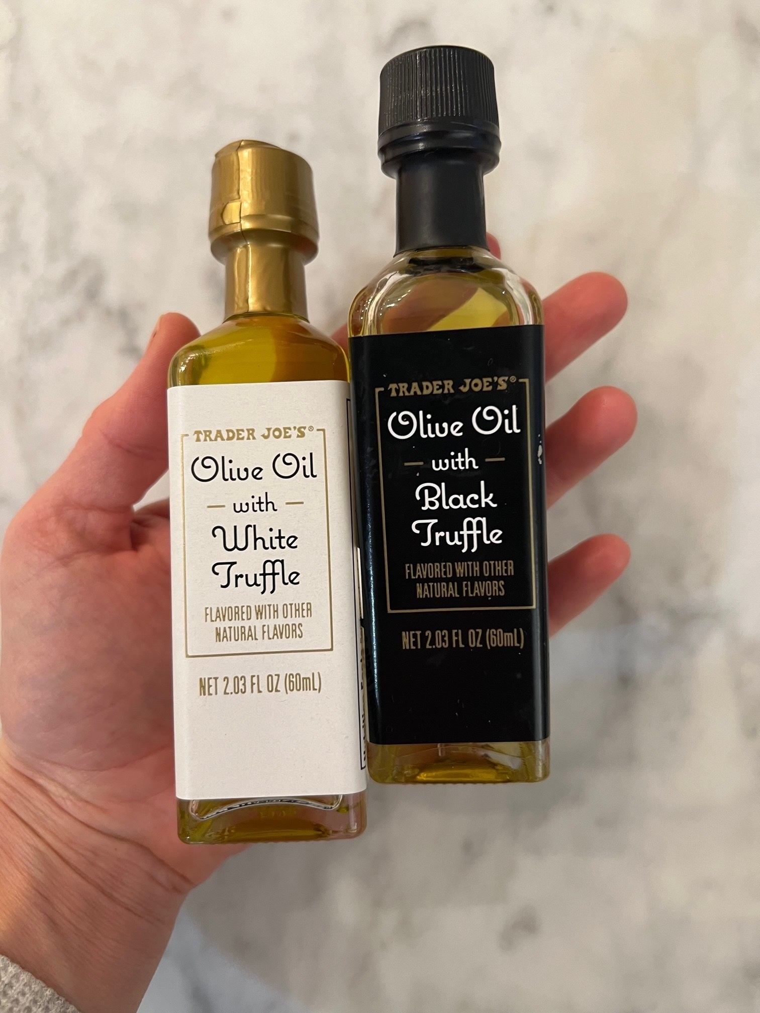 A hand holding two bottles of truffle olive oil