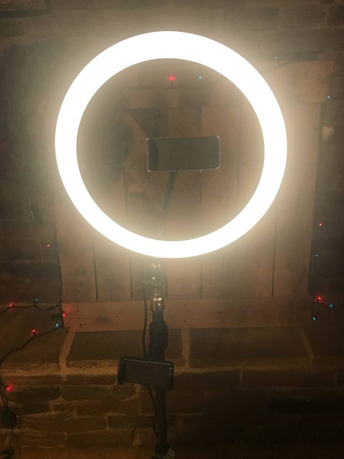 Reviewer&#x27;s photo of the ring light set up by desk with phone stand in the middle of light