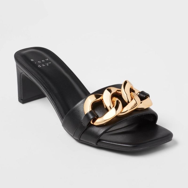 A pair of black shoes with heels with a gold chain