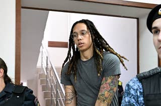 Brittney Griner wears handcuffs as she is escorted by two guards