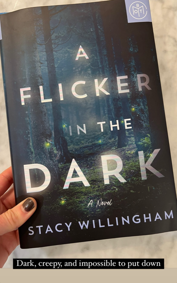 A hand holding &quot;A Flicker In The Dark&quot; by Stacy Willingham