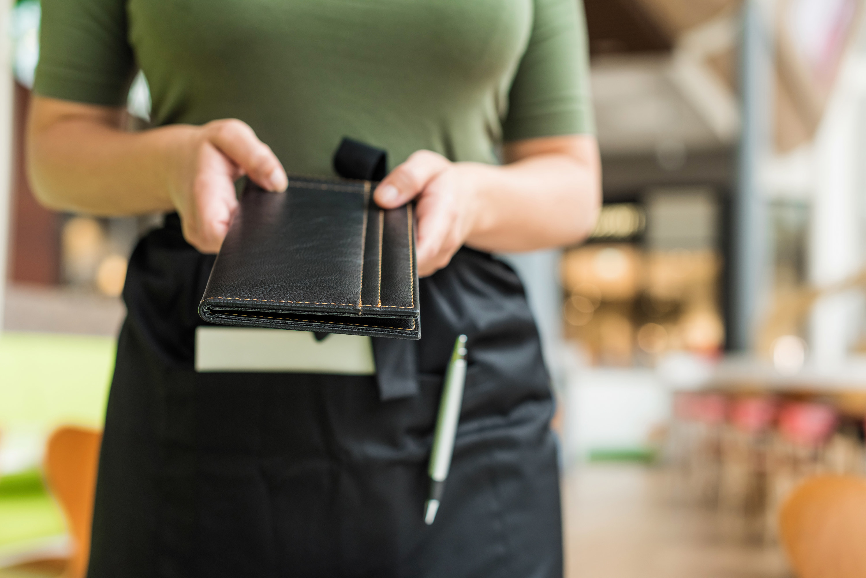 close up of a server handing over a check book