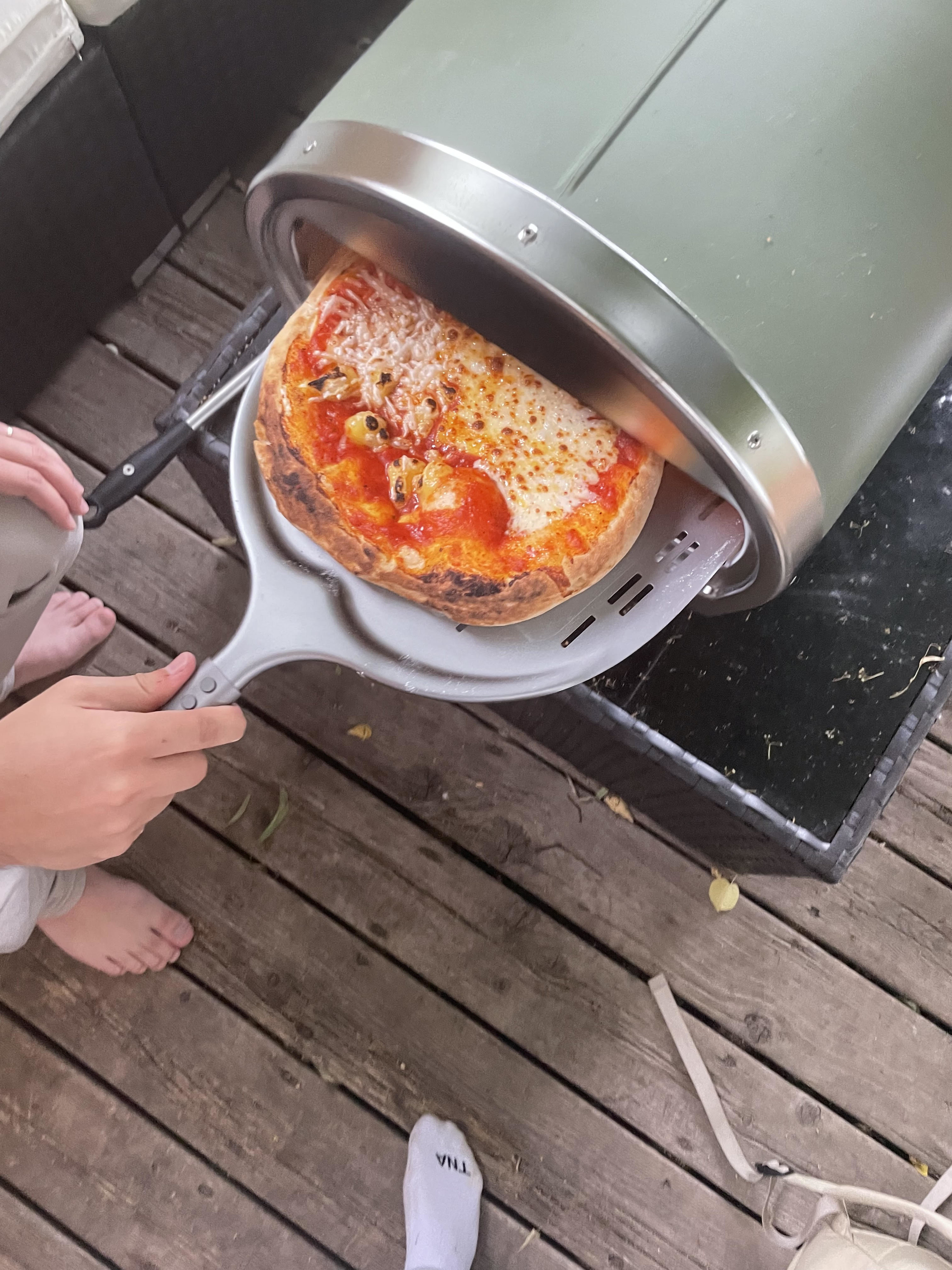 A person removing a pizza from the oven