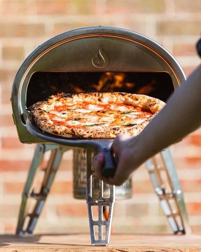 A person putting a pizza into the oven
