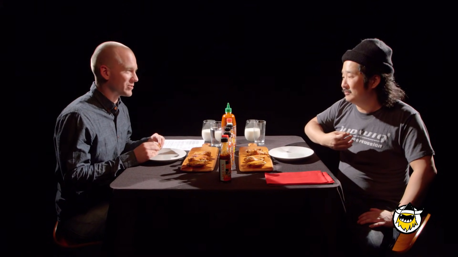 Sean Evans and Bobby Lee sitting across from each other in an episode of Hot Ones