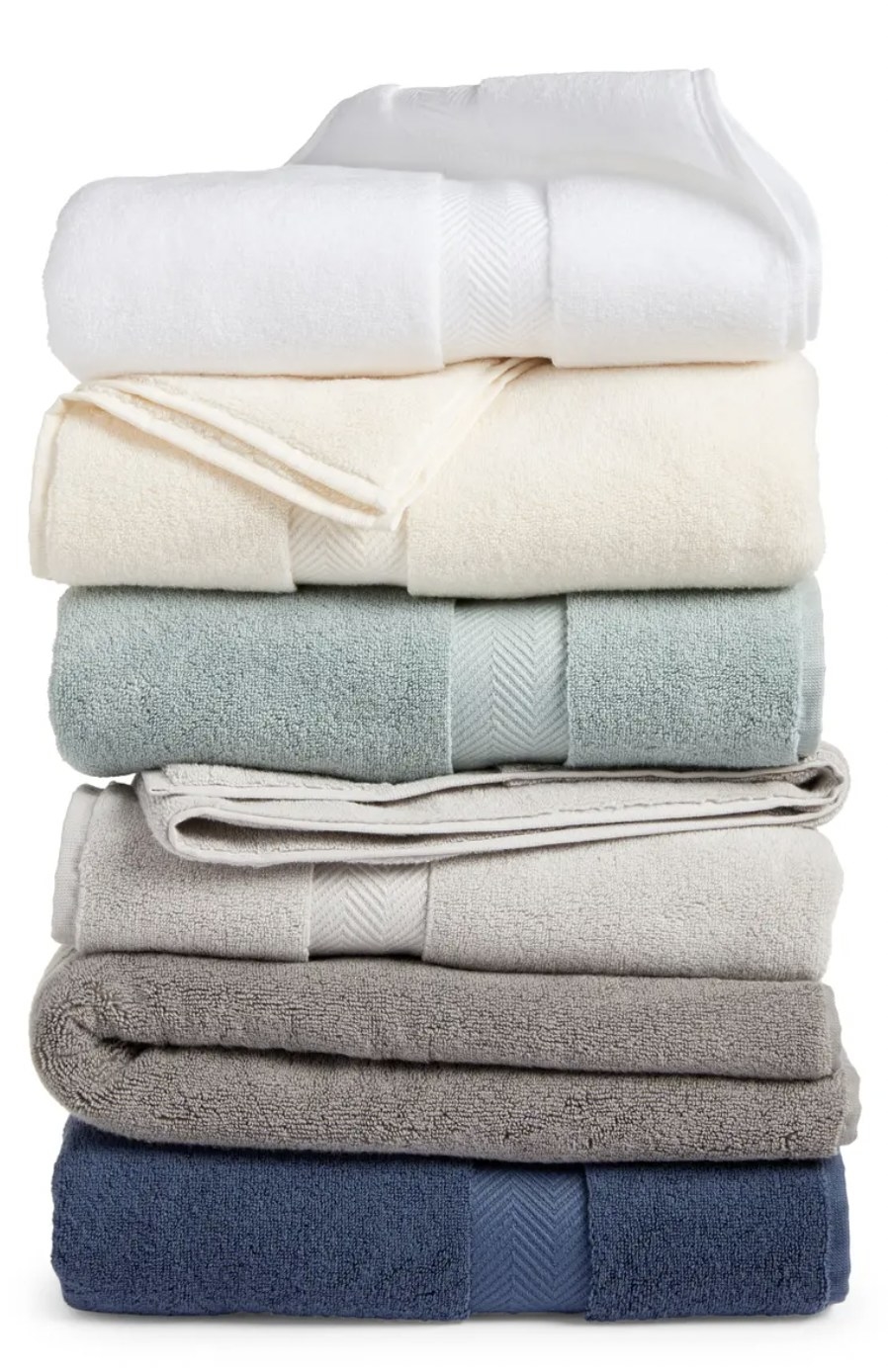 A stack of different colored towels, including dark blue, teal, different shades of grey, cream and white